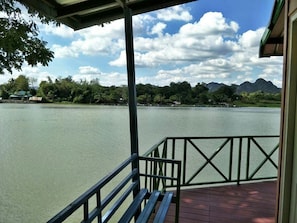 A view from a covered deck overlooking a calm lake with mountains in the distance. - Golden Dragon Resort (Kanchanaburi)
