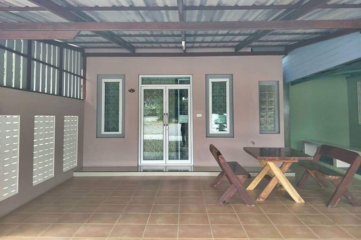 Ein überdachter Patio-Bereich mit Fliesenboden, einem Glastür-Eingang und einem Tisch mit Stühlen.