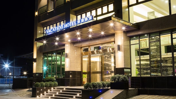 Een modern hotel met een opvallend bord, grote ramen en een goed verlichte ingang.