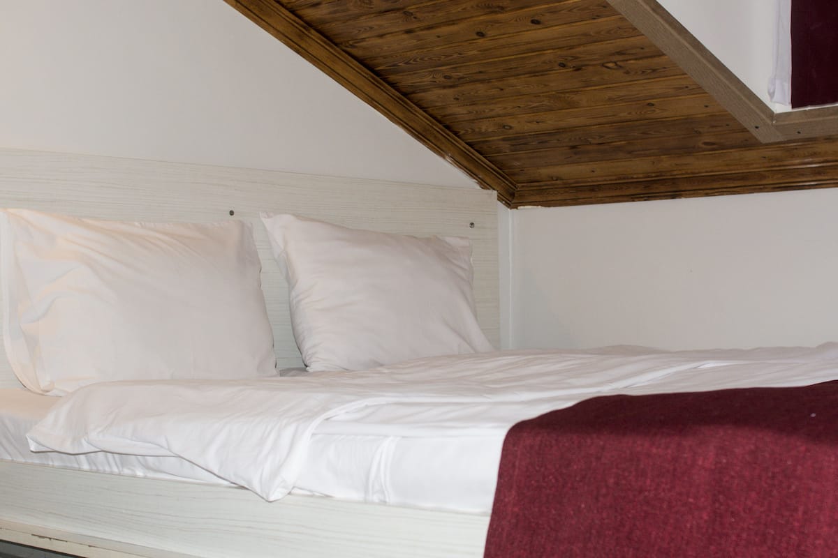 A single bed with white bedding in a room with a sloped ceiling.