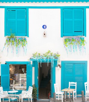 A building with turquoise shutters, a small birdhouse, hanging plants, and outdoor seating. - Hot Budget (Istanbul)