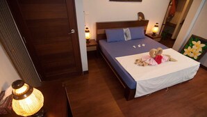 A bedroom with a bed, pillows, a bedside lamp, and a wall painting. - Penn Sunset Villa with Pool 10A (Ko Lanta)