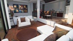 A modern living room with a sofa set, a round coffee table, and a dining area with a table and chairs. - Penn Sunset Villa with Pool 10A (Ko Lanta)