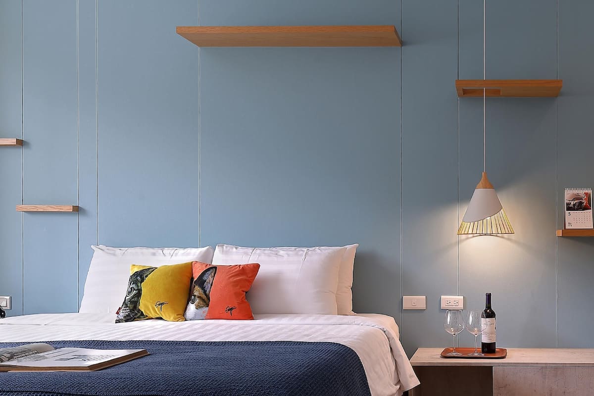 Quarto de hotel moderno com cama, mesa de cabeceira e escrivaninha com cadeira.