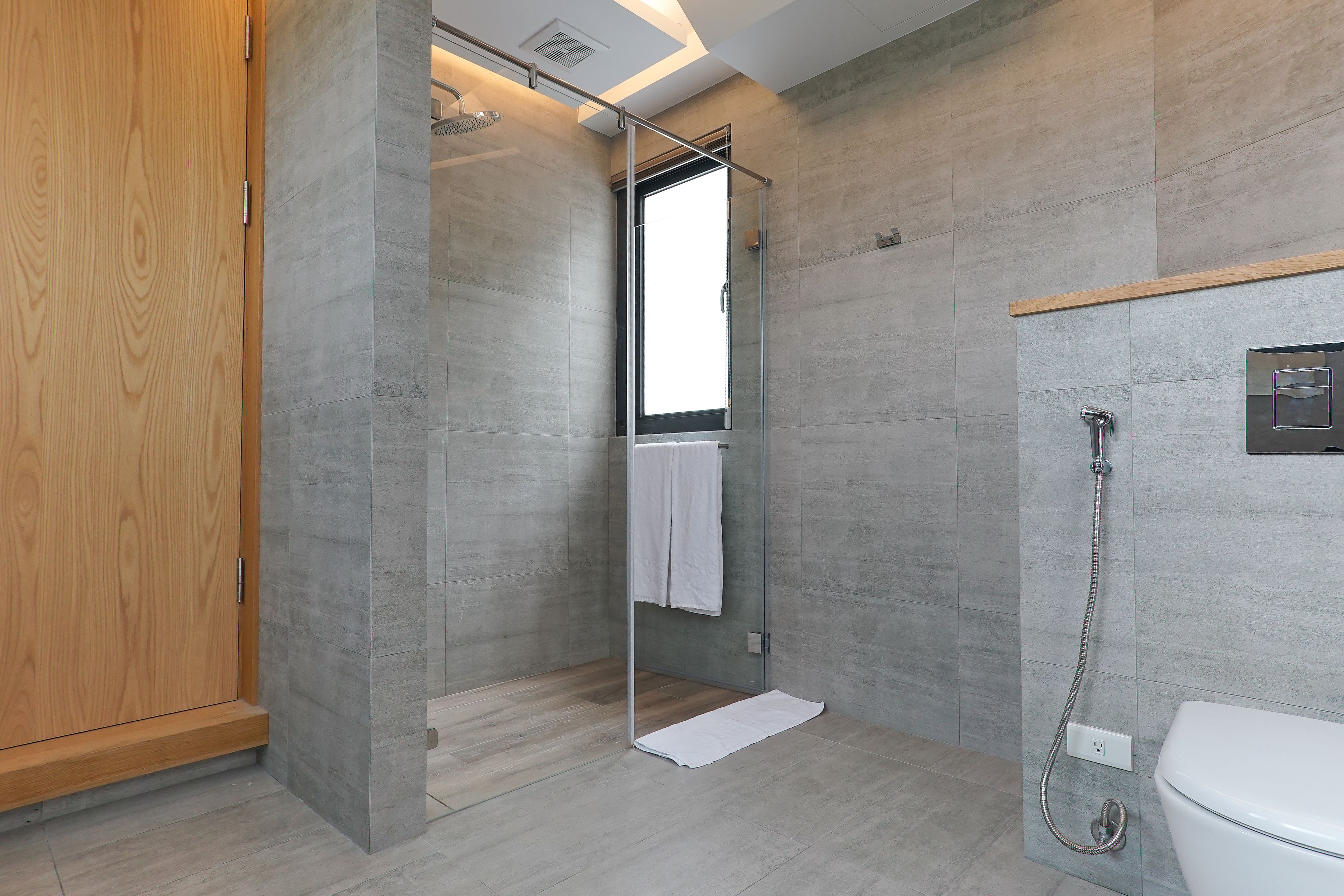 Een moderne badkamer met een douchecabine van glas, een houten garderobe en een wit toilet.