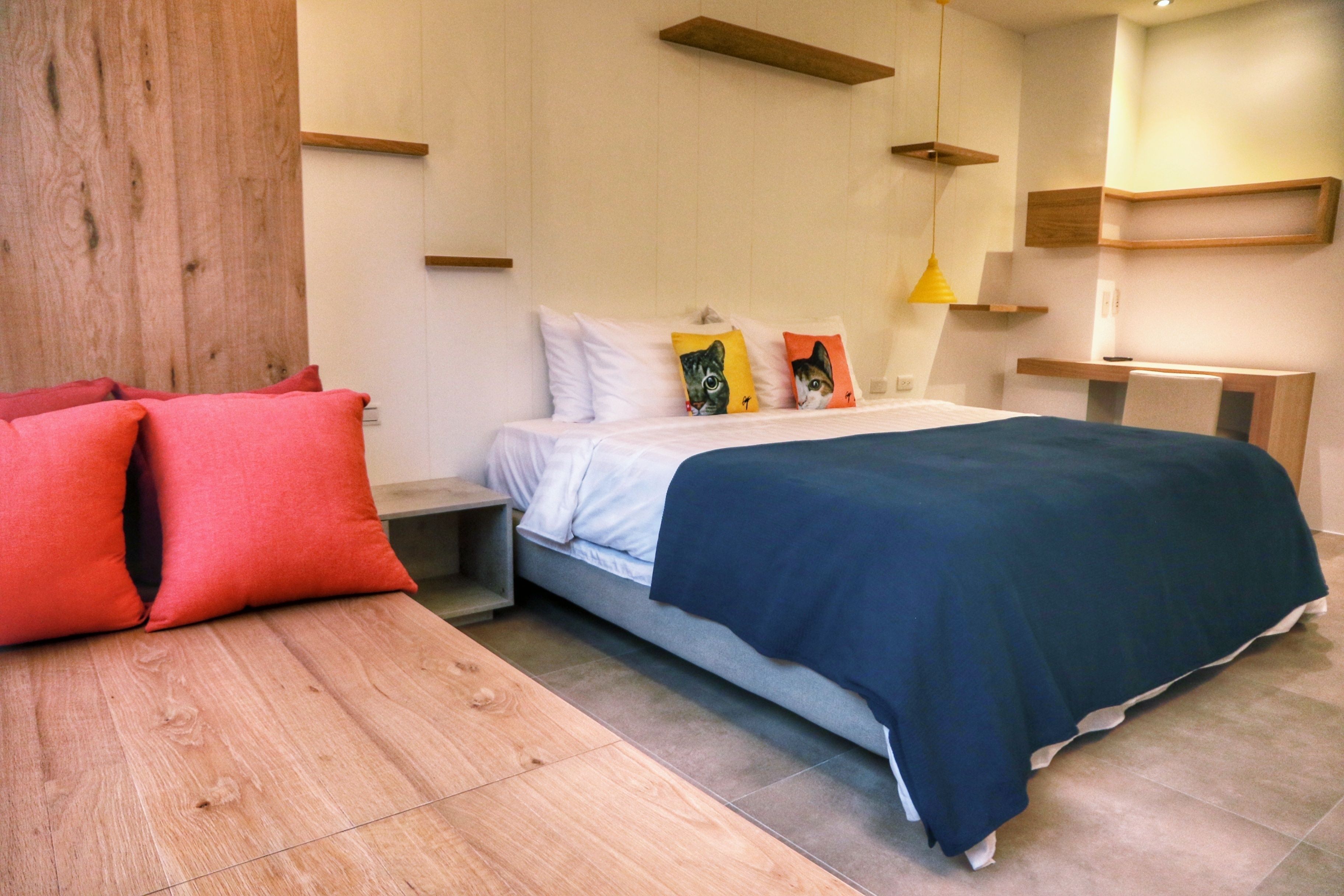 A modern bedroom with a bed, nightstands, a wooden bench, and a desk.