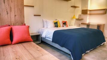 A modern bedroom with a bed, nightstands, a wooden bench, and a desk.