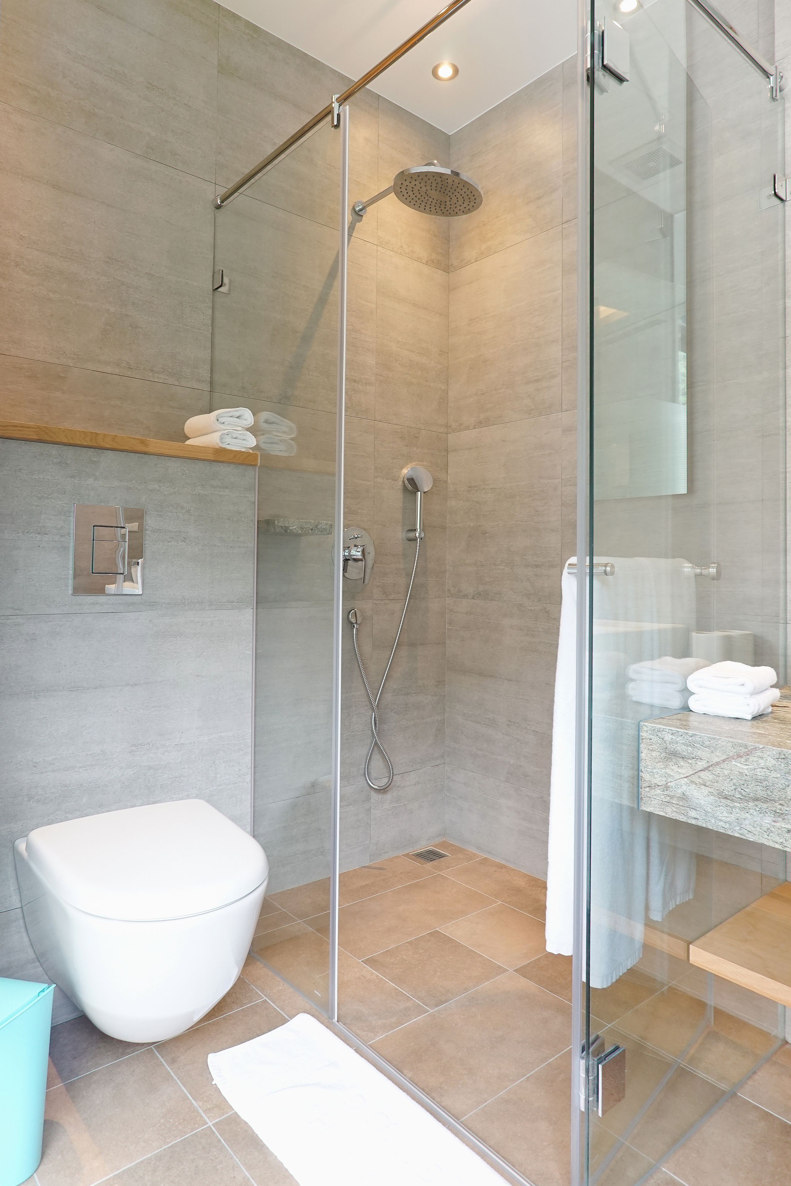 A modern bathroom with a glass-enclosed shower, a white toilet, and a marble countertop.