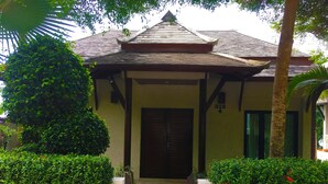 A traditional building with a tiled roof, a wooden staircase leading to a door, and well-maintained greenery around it. - Penn Sunset Villa 4 (Ko Lanta)