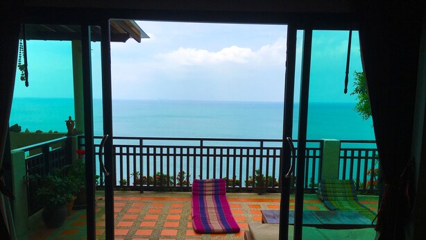 A balcony with a view of the sea, a patterned floor, and a bed with a blanket. - Penn Sunset Villa 4 (Ko Lanta)