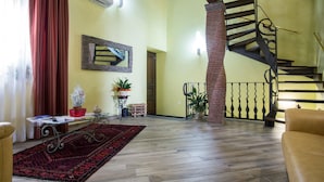 A spacious living area with a wooden floor, a red curtain, a staircase, and a sofa. - L'Arco dei Sogni (Malvagna)