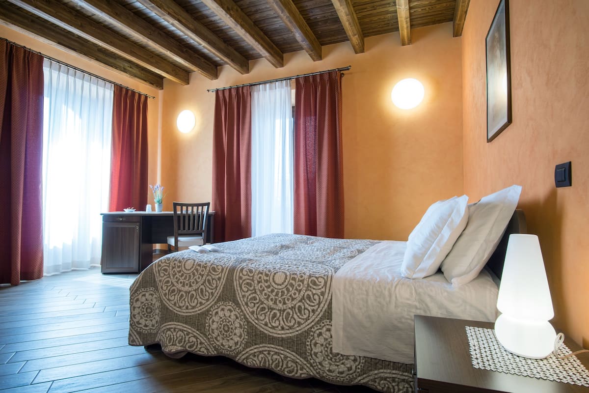 Een slaapkamer met een bed, een bedlampje en gordijnen.