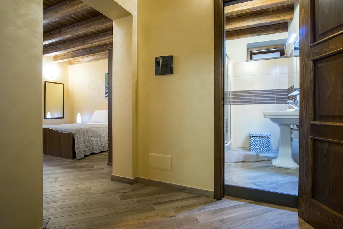 Een gang met houten vloer die leidt naar een slaapkamer en een badkamer.