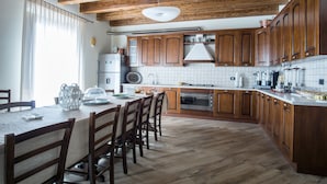 A modern kitchen with wooden cabinets, a central island, and a dining area with chairs. - L'Arco dei Sogni (Malvagna)