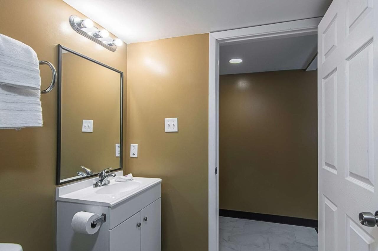 A bathroom with a white sink, mirror, and towel ring.