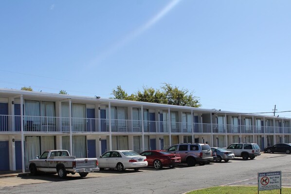 A motel with a row of rooms, a parking lot, and a sign indicating it's for dog owners.