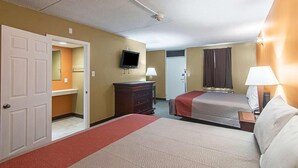 A hotel room with two beds, a television, a dresser, and a door leading to a bathroom. - LoneStar Inn & Suites (Sherman)