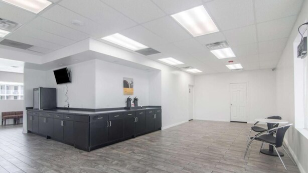 A spacious, modern kitchen with dark cabinetry, a built-in island, and a flat-screen TV mounted on the wall. - LoneStar Inn & Suites (Sherman)