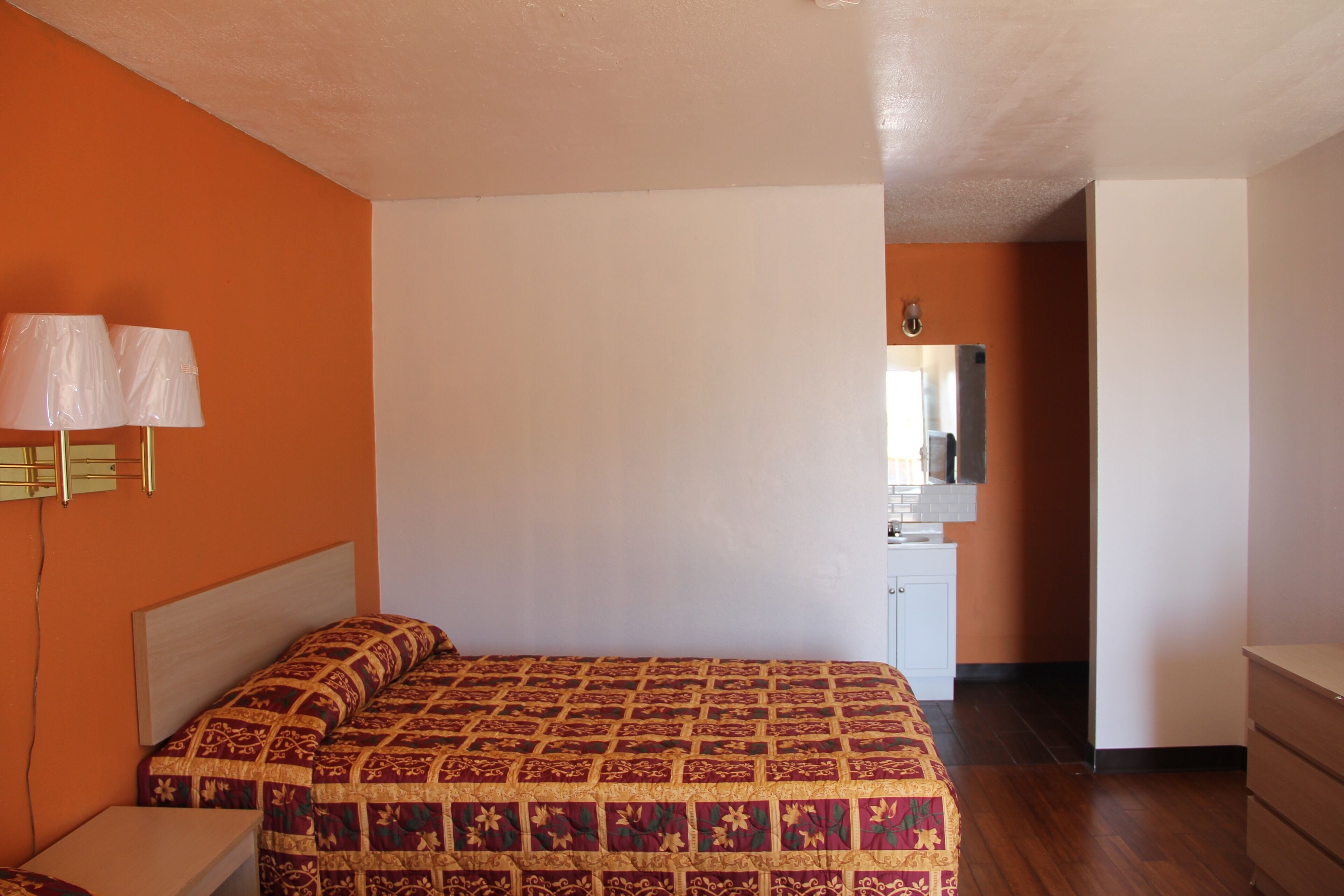 Une chambre à coucher avec un lit, une table de chevet, une commode et un miroir.
