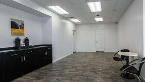 A modern kitchen with black cabinets, a coffee station, and a white door. - LoneStar Inn & Suites (Sherman)