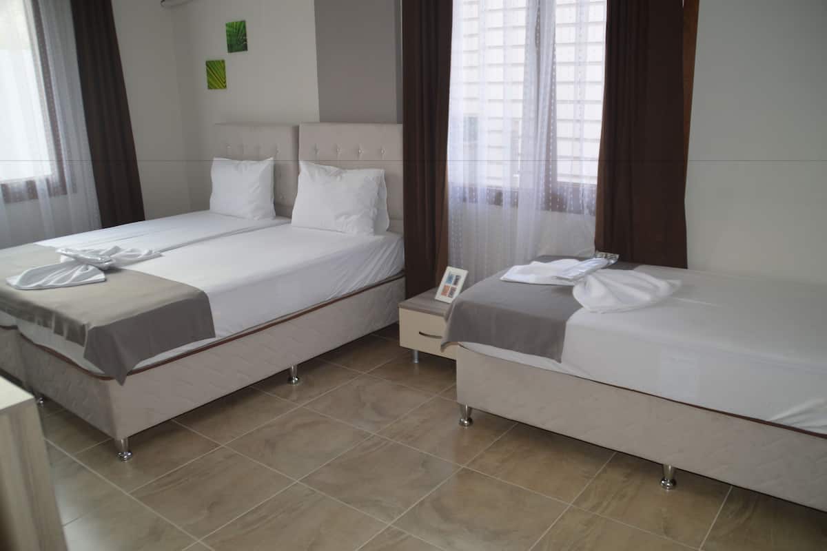 A hotel room with two beds, a bedside table, and a window with curtains.