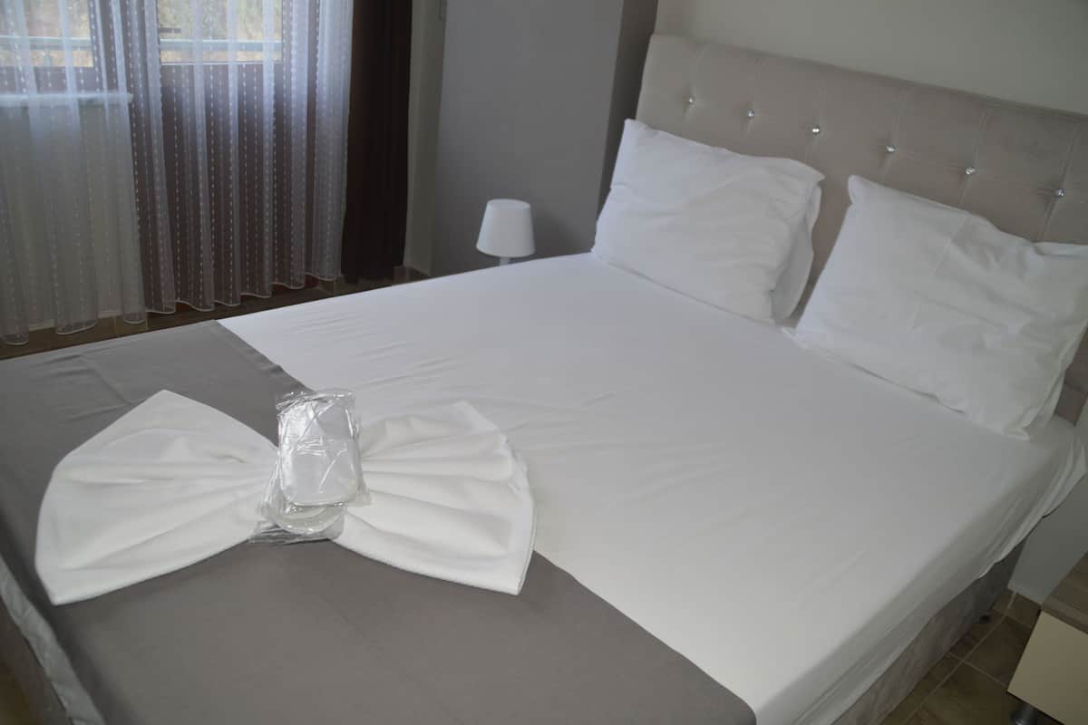 A neatly made bed with white linens and a bow on the bedspread.