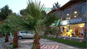 A hotel named "Hotel Hugo" with a paved entrance and palm trees. - Hotel Hugo (Edremit)