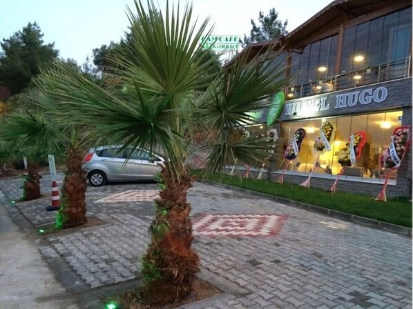 A hotel named "Hotel Hugo" with a paved entrance and palm trees. - Hotel Hugo (Edremit)