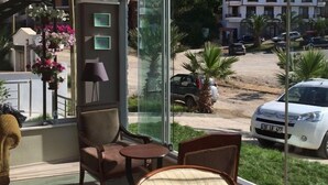 A room with a large window, a chair, a small table, and a lamp. - Hotel Hugo (Edremit)