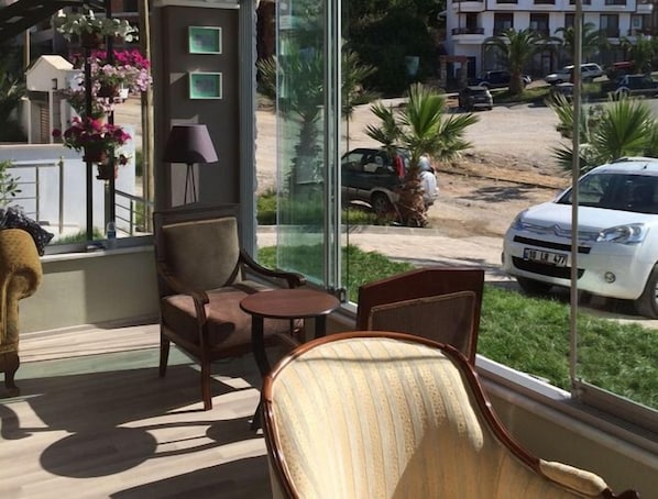 Une pièce avec une grande fenêtre, une chaise, une petite table et une lampe.