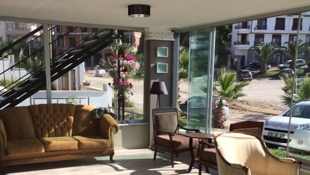 A spacious living area with a sofa, chairs, and a table. A staircase is visible in the background, leading to an upper floor. - Hotel Hugo (Edremit)