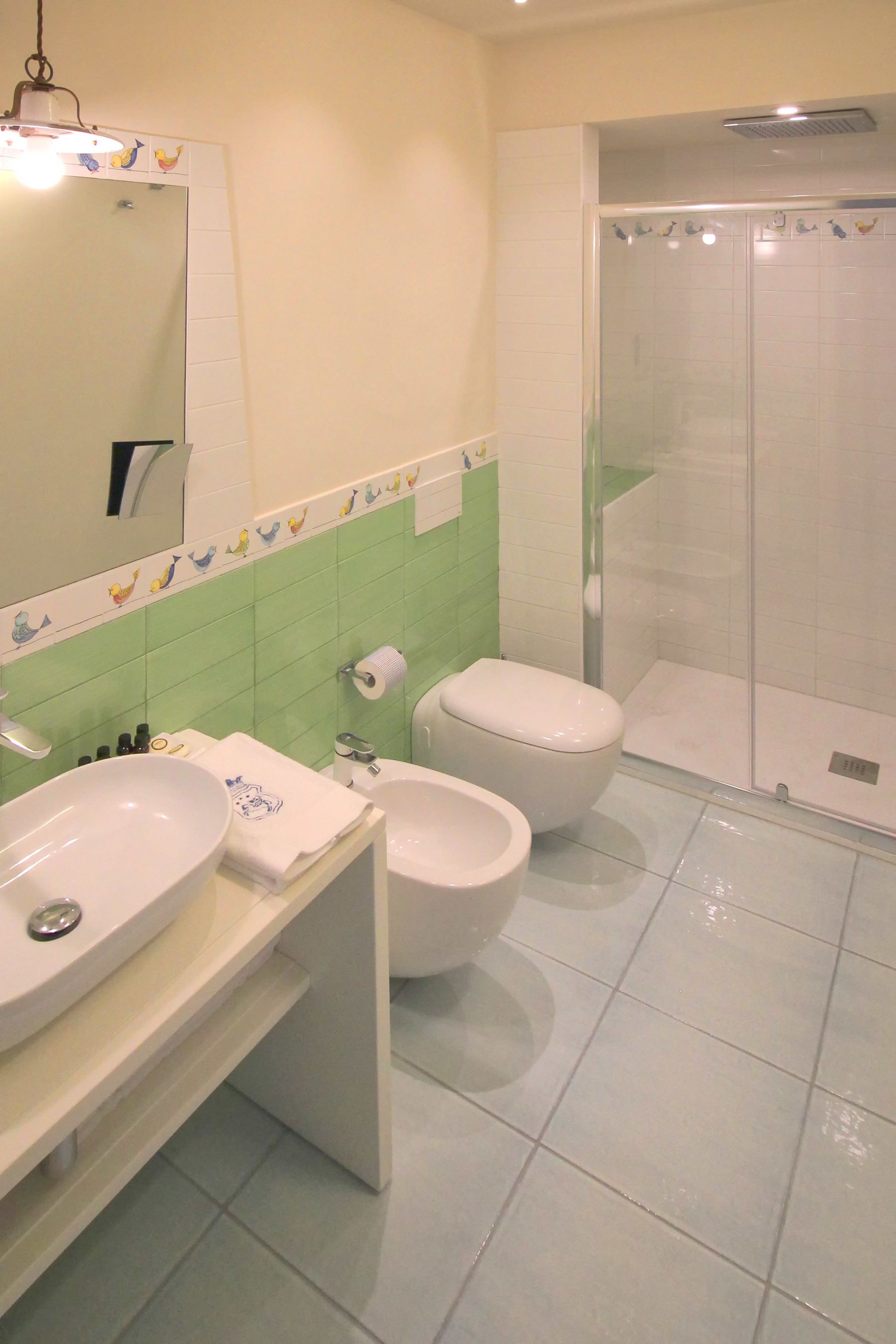 Un bagno con due lavandini, un water e una cabina doccia in vetro.
