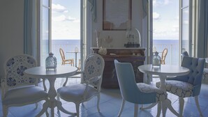 A dining area with a view of the sea, featuring white and blue patterned chairs and a white table. - Palazzo Mottola Tropea (Tropea)