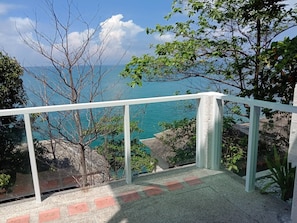 Ein Balkon mit freiem Blick auf das Meer und die umliegenden Bäume.