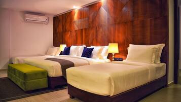 Una habitación de hotel con dos camas, un reposapiés verde y una pared de acento de madera.