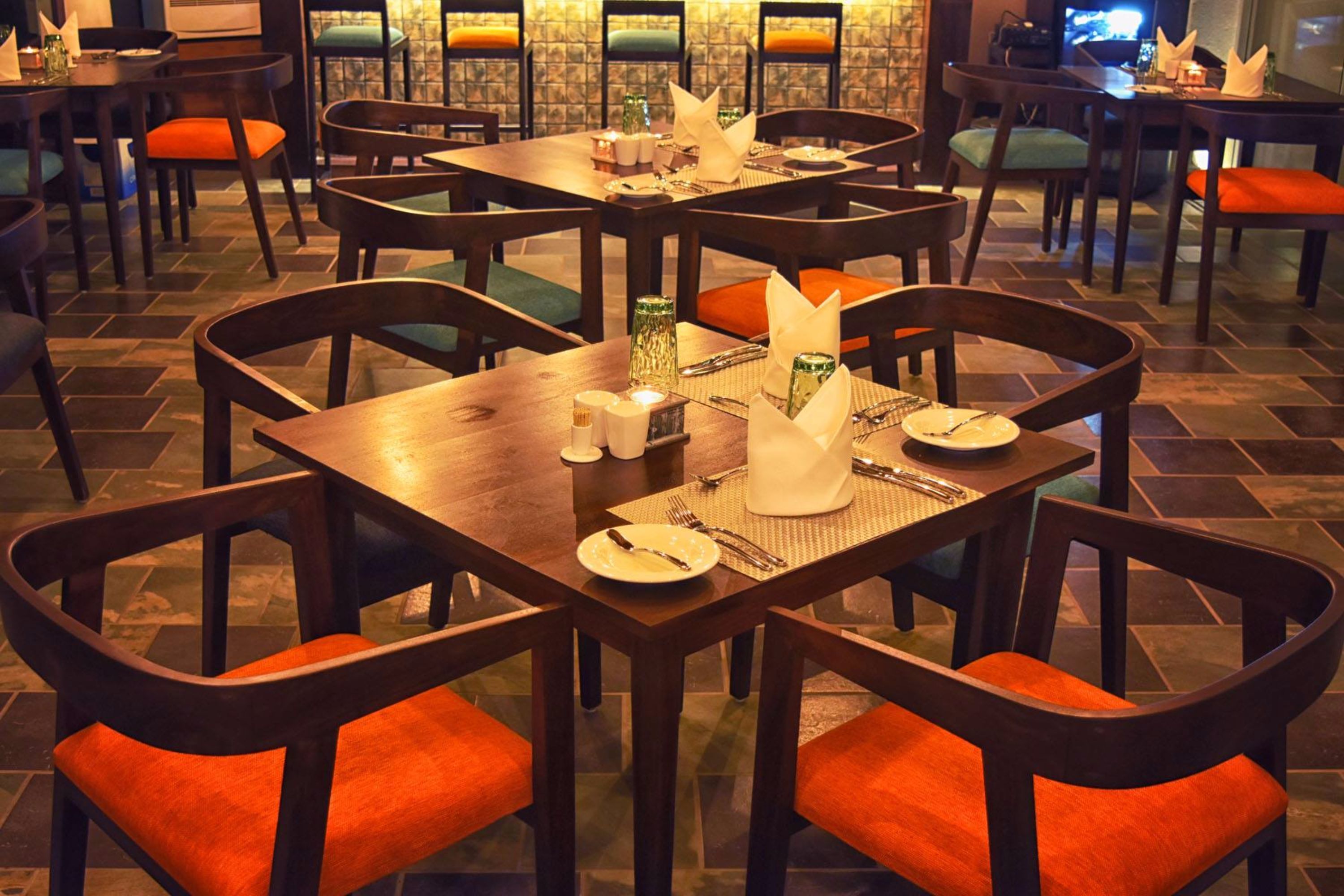 A restaurant with multiple tables and chairs, each set with plates, cutlery, and napkins.