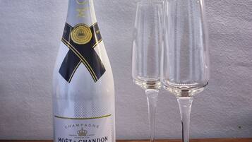 A bottle of Moët & Chandon Ice Imperial champagne and two empty champagne flutes on a wooden table.