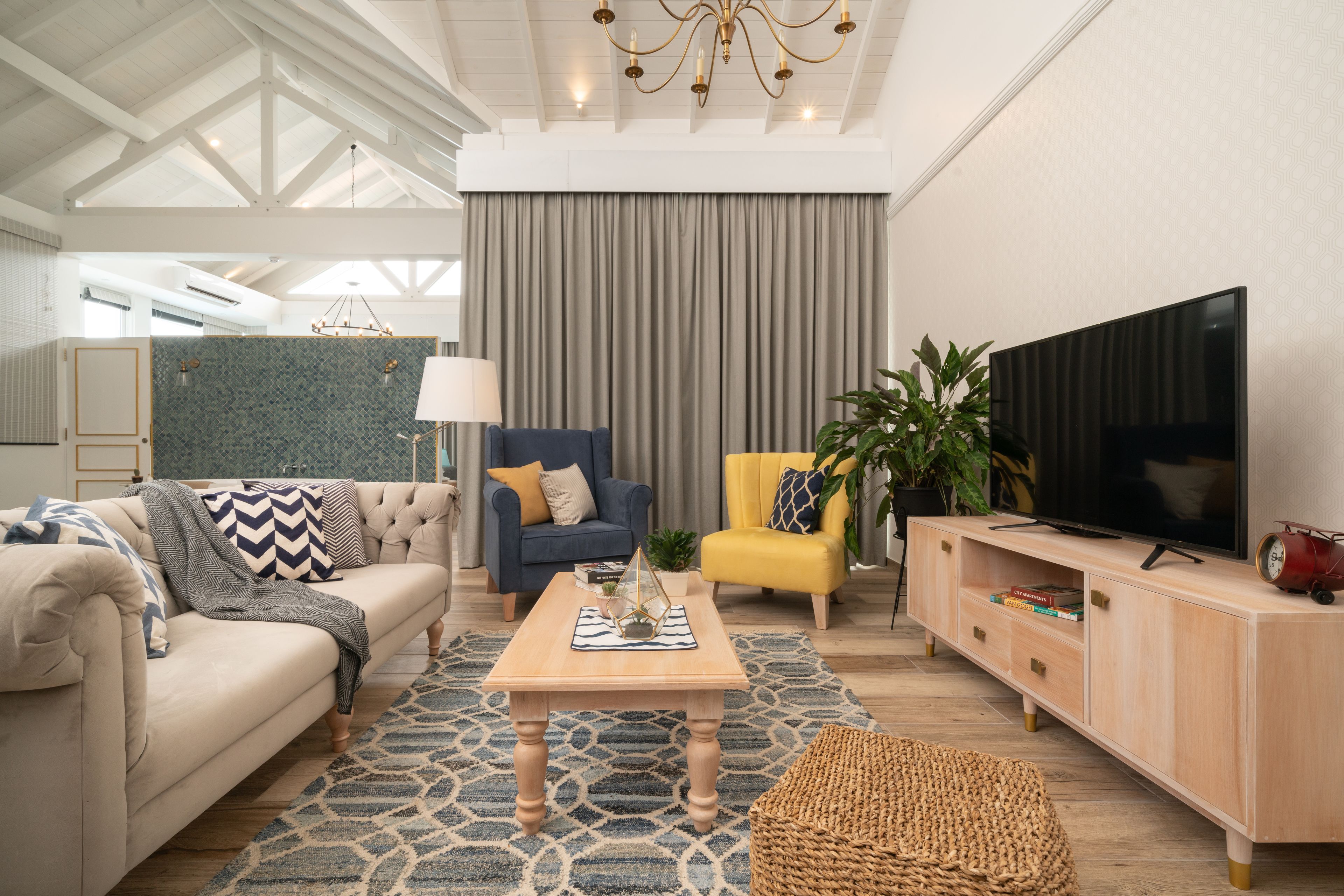 A modern living room with a sofa, armchair, coffee table, and television.