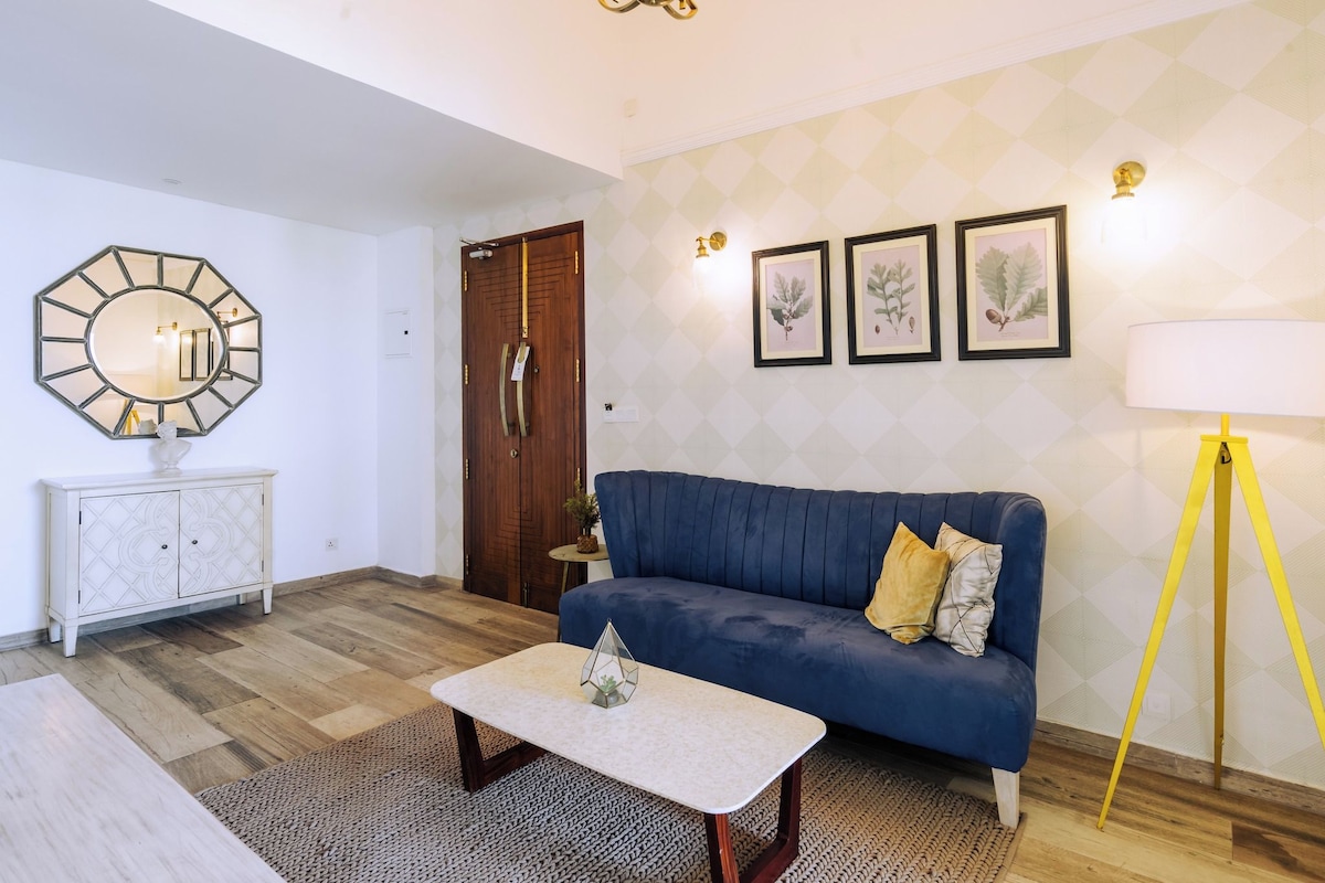 A living room with a blue sofa, a white coffee table, a wooden cabinet, and a large mirror.