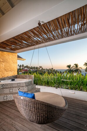 A wooden deck with a hanging wicker chair, a built-in hot tub, and a view of the ocean and palm trees. - Triple O Six (Mirissa)