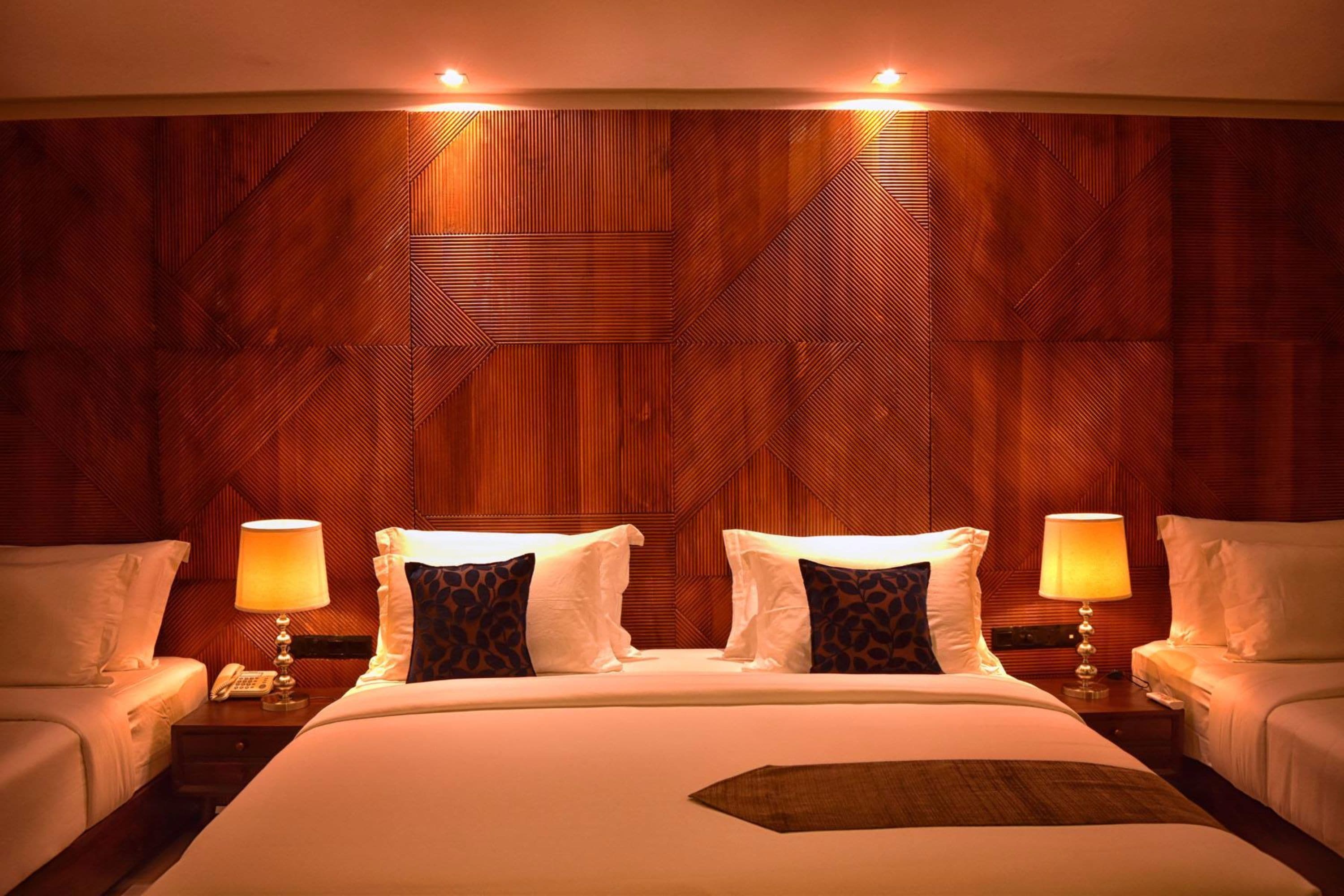 A hotel room with a large bed, two bedside tables with lamps, and a wooden headboard.