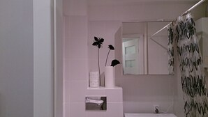 A bathroom with a white sink, a mirror, and a shower curtain with a black pattern.