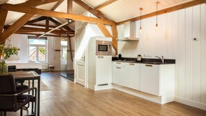 Una cocina moderna con armarios blancos, microondas integrado y luces colgantes.