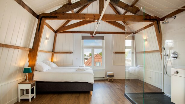 Un dormitorio con cama, mesita de noche y cabina de ducha de vidrio.