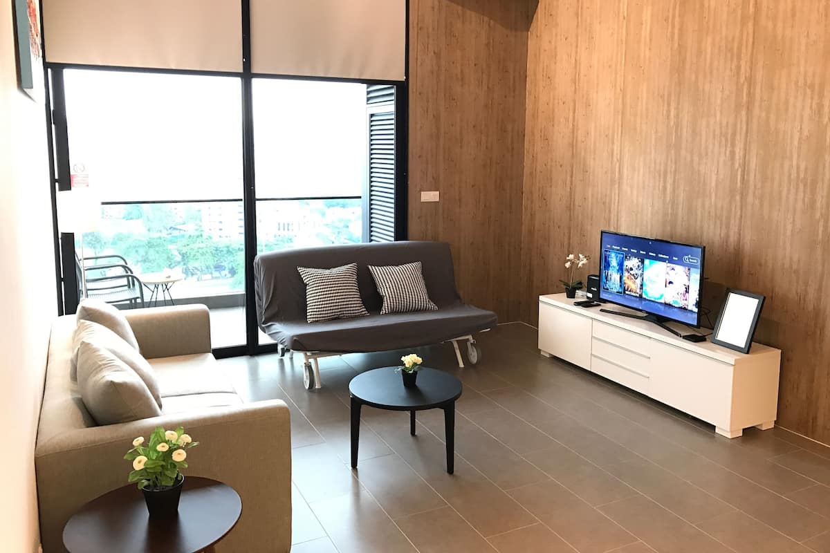 A modern living room with a sofa, a coffee table, a TV, and a small side table.