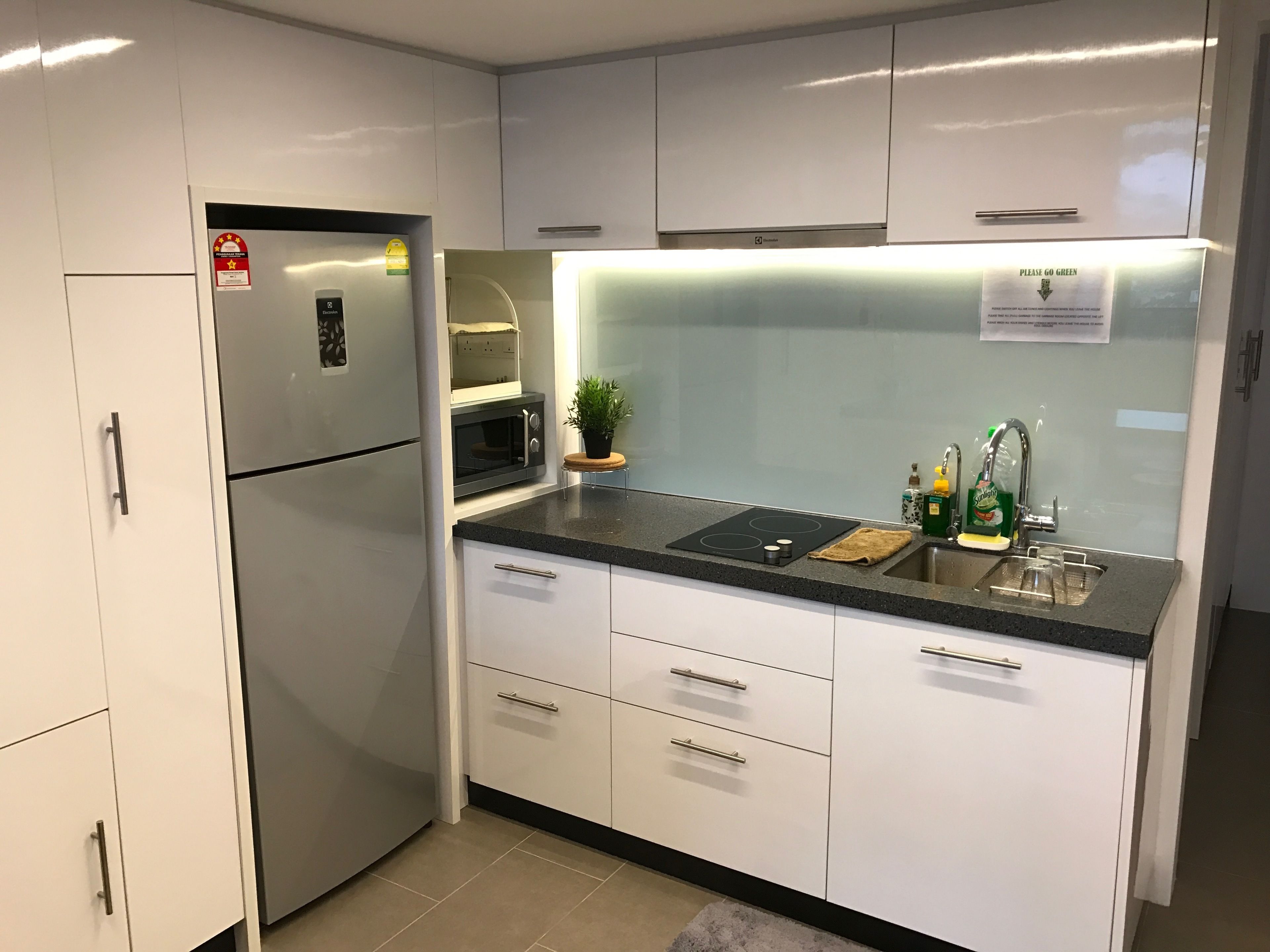 A modern kitchen with white cabinets, a built-in oven, a microwave, and a sink with a faucet.