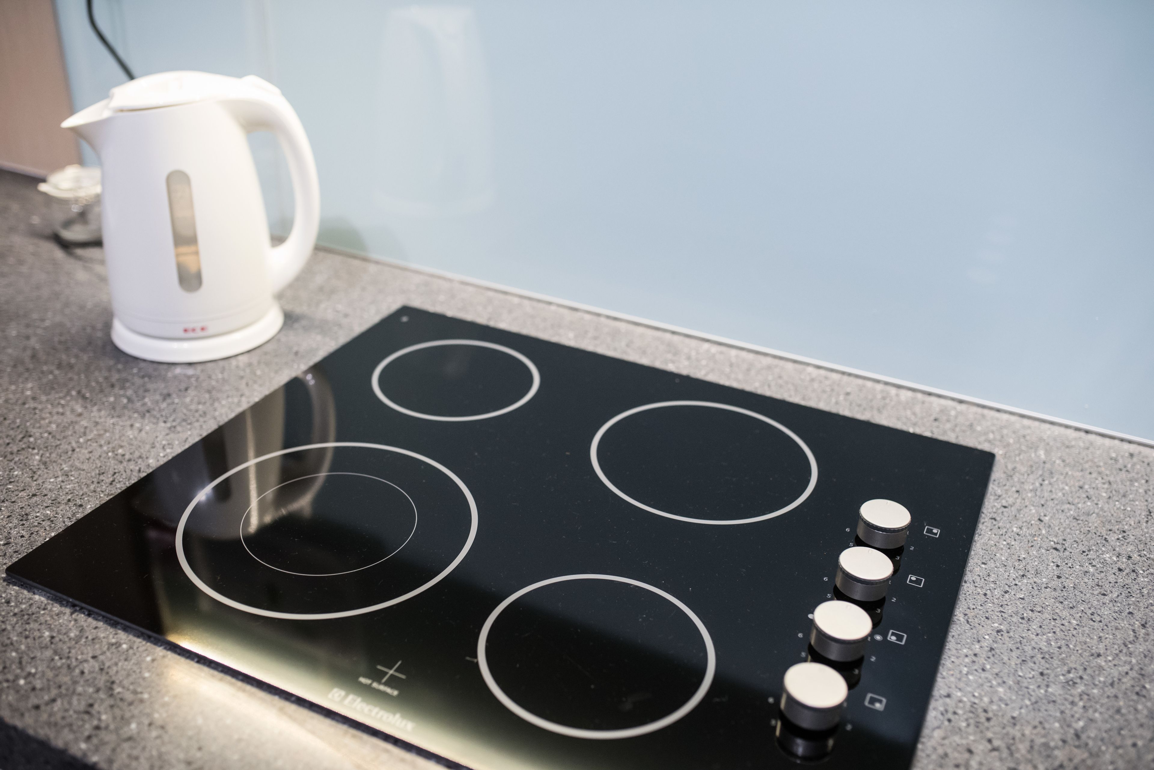 A kitchen with a black induction cooktop and a white electric kettle on the counter.