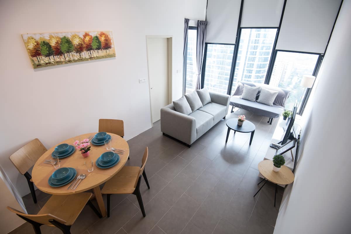 A modern living room with a sofa, a dining table set with blue plates, and a painting on the wall.