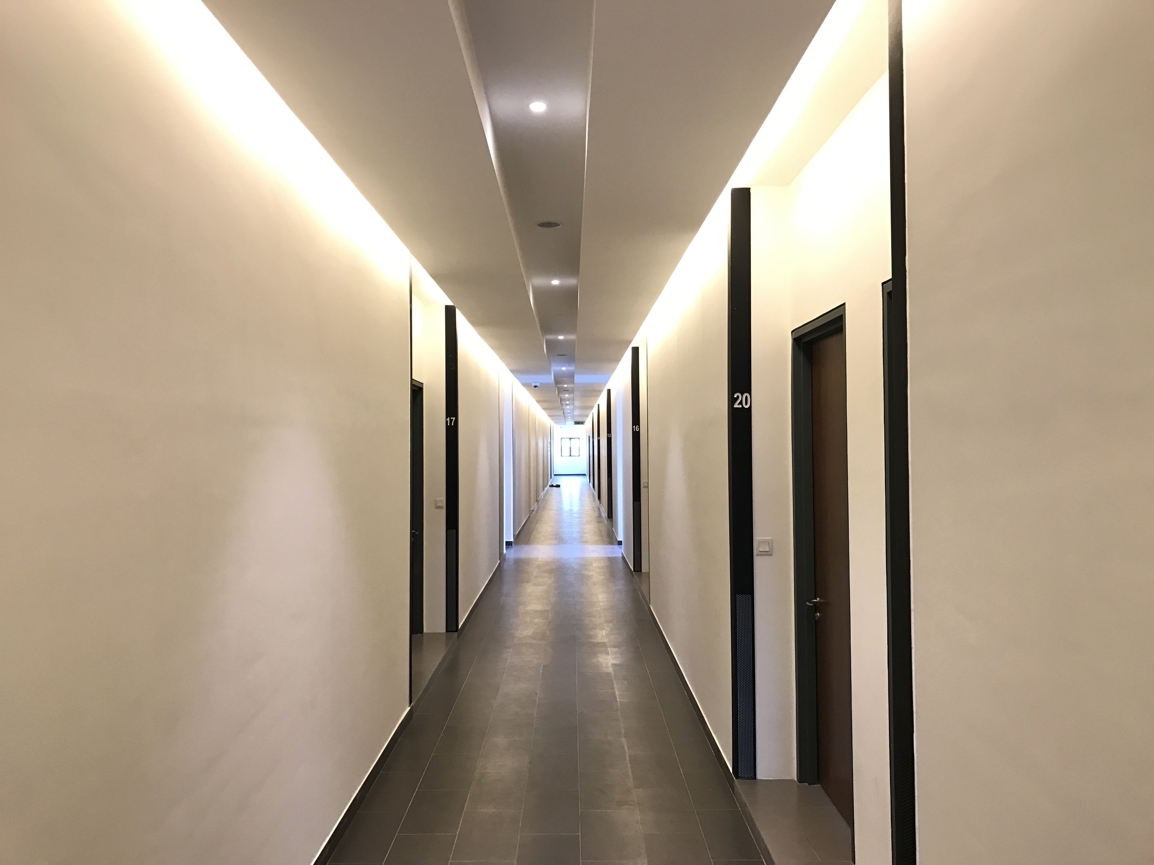 A long, well-lit hallway with doors numbered 16 to 20.