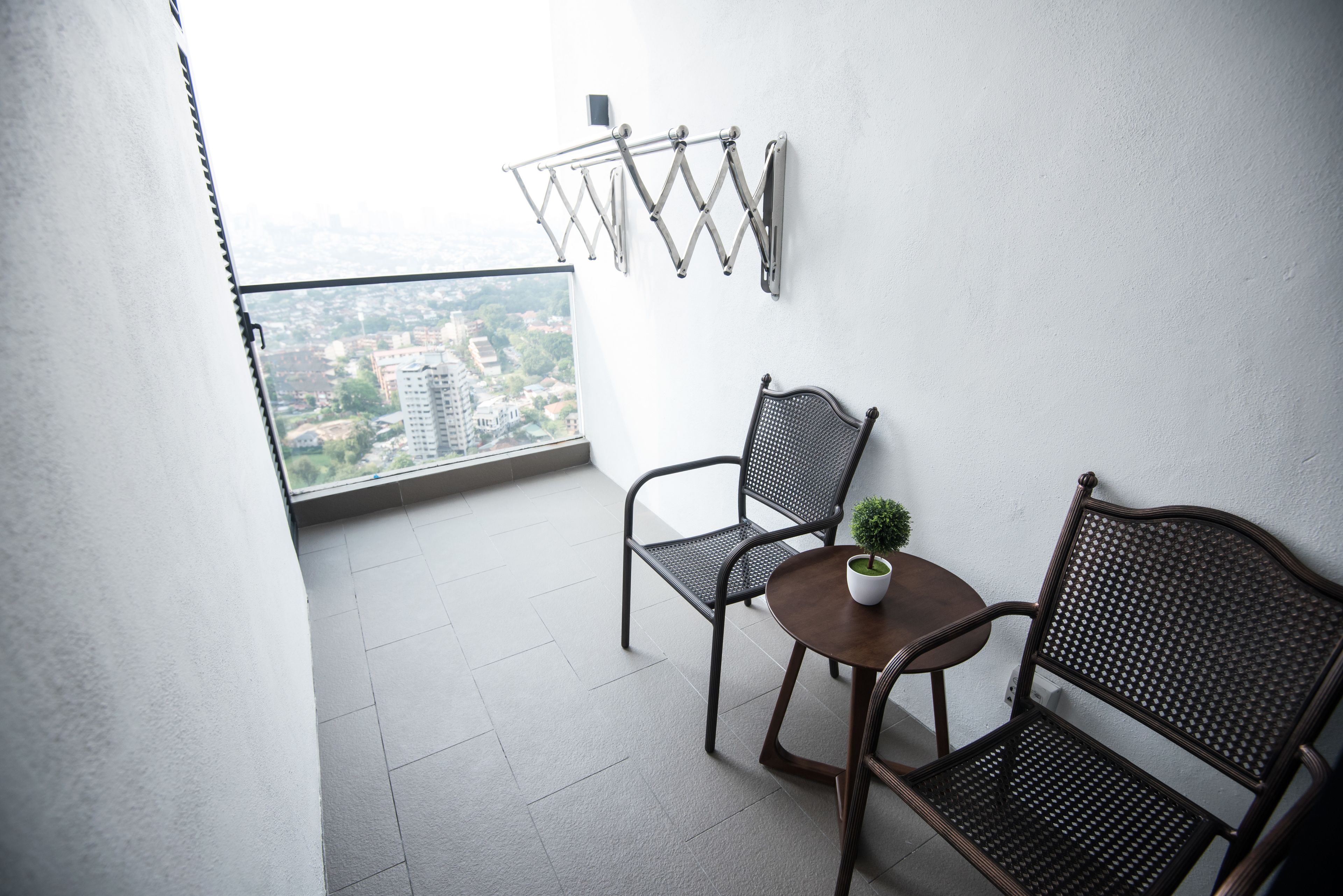 Un balcon avec deux chaises, une petite table et un pot de fleurs.